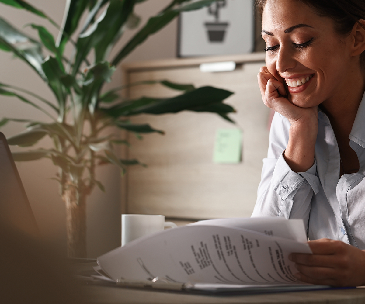 Happy female entrepreneur analyzing business reports and feeling satisfied about the business progress.